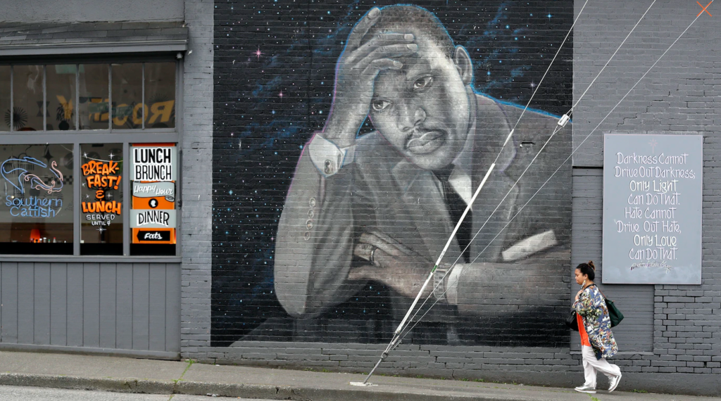 A person walks past a large mural of the Rev. Martin Luther King Jr. on the side of a diner.