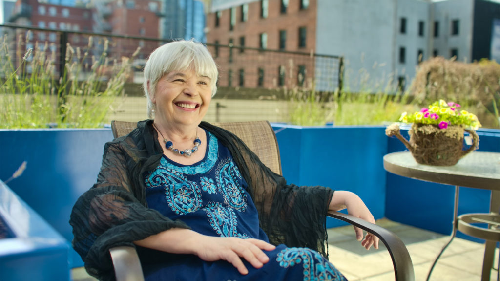 An elderly woman relaxing on a blue patio chair.