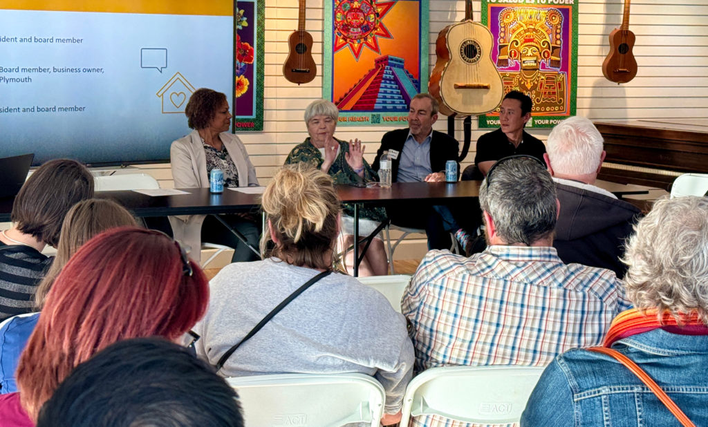 Audience seated in chairs facing a screen, attentively watching a presentation.