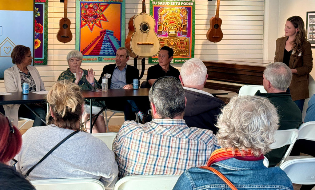 A group of people are seated at the back of a room in front of an audience