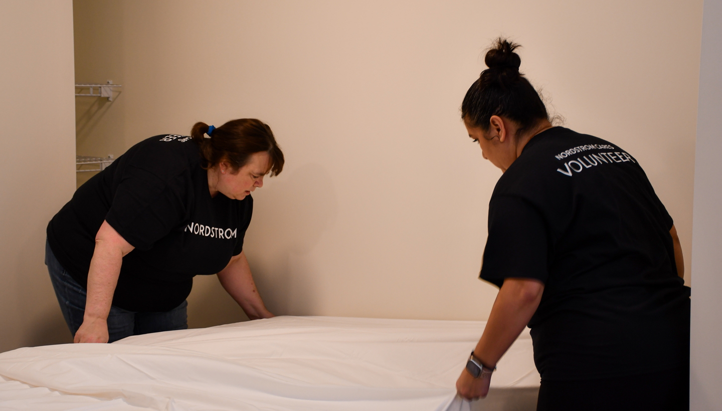 Nordstrom volunteers make a bed