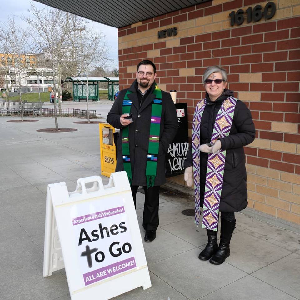 Two people standing outside providing ashes on Ash Wednesday