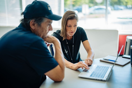 A person at a laptop talking to another person at a desk